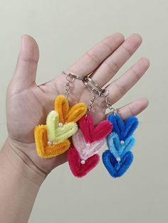 the hand is holding three small key chains