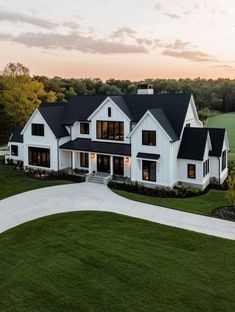 an aerial view of a large white house with black roof and dark shingled windows