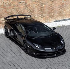 a black sports car parked in front of a brick wall