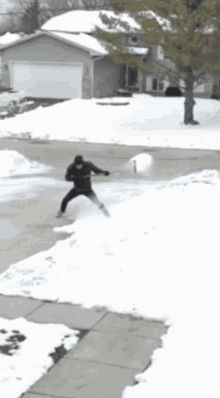 a person on skis in the middle of a driveway with snow all over it