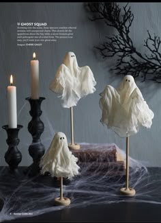 three candles and some fake ghost decorations on a table