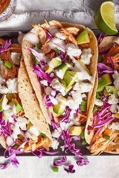 three tacos with shredded cabbage, chicken and avocado
