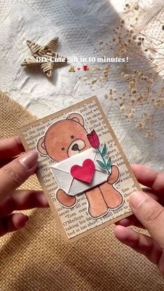 someone is holding up a card with a teddy bear and heart in the envelope on it