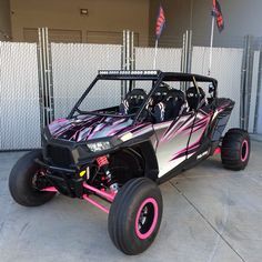 a pink and black dune buggy parked in front of a building