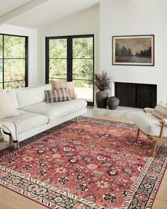 a living room filled with furniture and a large rug on top of a hard wood floor