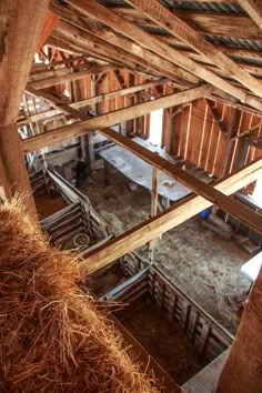 the inside of a barn with wooden beams and straw bales on the floor below