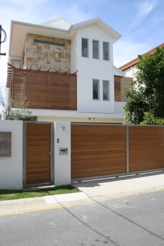a white house with wooden slats on the front and side walls, along with a fence