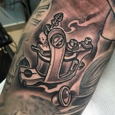 a man's arm with a black and grey tattoo design on it, including an anchor