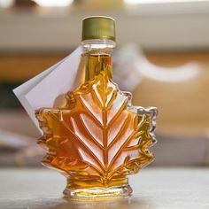 a bottle of maple syrup sitting on top of a table next to a paper boat