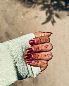 a woman's hand with red nail polish holding onto a towel over her arm