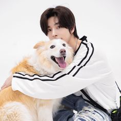 a person sitting on the ground with a dog in their lap and his arm around him