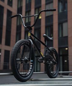 a black bike parked in front of a tall building on a city street with no one around it