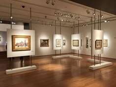an art gallery with paintings on the walls and wooden floors