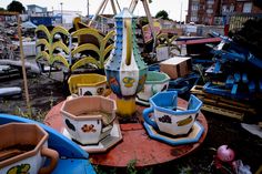 an old abandoned carnival ride with lots of seats and buckets on the ground in front of it