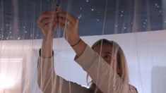 a woman is holding something up to the ceiling with her hands and looking at it