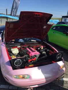 a pink sports car with its hood open and the engine in it's trunk