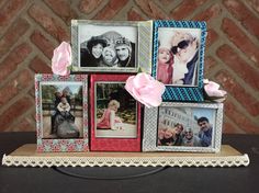 there are many pictures on the table with pink flowers in front of them and two roses sticking out of the frame