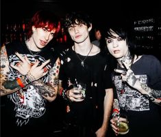 three young men standing next to each other at a bar with tattoos on their arms