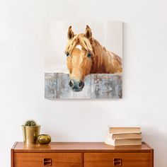 a painting of a brown horse with blue eyes on a white wall above a dresser