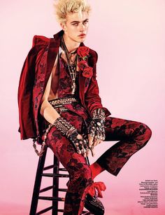 a woman sitting on top of a stool wearing a red suit and black pants with flowers in her hair