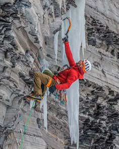 a man climbing up the side of a mountain with ice hanging off of it's sides