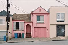 three houses are painted pink and white on the street