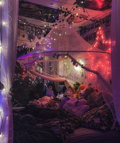 a room with lights and decorations on the ceiling, including a canopy bed covered in stuffed animals