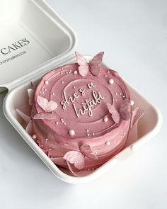 a pink cake in a white box with butterflies on it and the words she's so happy