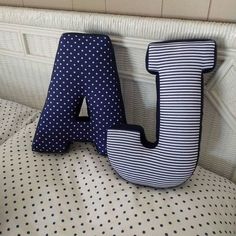 the letter j is made out of fabric and sits on a bed with polka dots