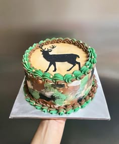 a hand holding a cake decorated with an image of a deer