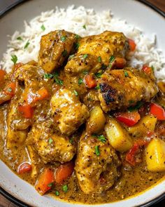 a white bowl filled with chicken and vegetables next to rice on top of a wooden table