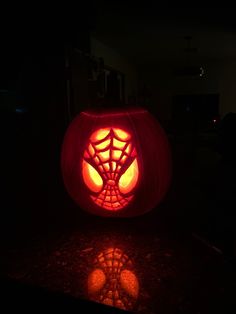 a pumpkin carved to look like a spiderman's web in the dark with its eyes glowing