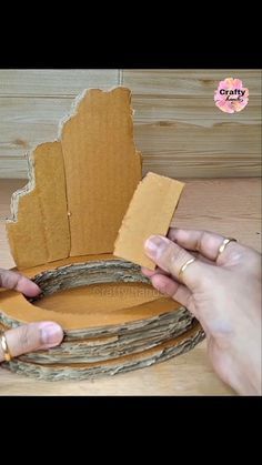 two hands are making a cardboard crown out of paper and twine with scissors on the table