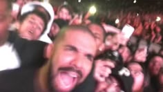 a large group of people at a concert with their mouths open and one person taking a selfie
