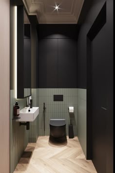 a bathroom with black and white walls, wood flooring and green tiles on the wall
