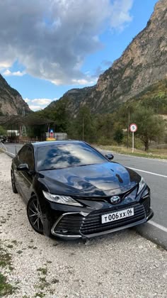 a black car is parked on the side of the road in front of some mountains