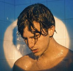 a man with wet hair standing in the shower
