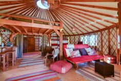 the inside of a yurt with wooden floors and walls, including a red couch