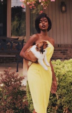 a woman in a yellow dress holding a dog