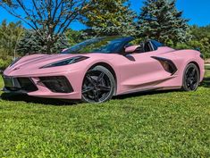 a pink sports car parked in the grass