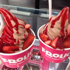 two ice cream cups filled with strawberries and chocolate