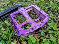a purple bike pedal sitting in the grass