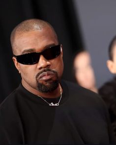 a man wearing sunglasses and a black t - shirt is standing in front of a crowd