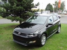 a black car is parked in the grass