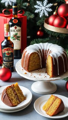 a bundt cake with white icing sitting on plates next to a bottle of booze
