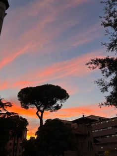 the sun is setting over some buildings and trees