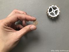 a person holding a piece of wood next to a small white object on a table