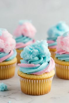 cupcakes with blue, pink and white frosting on them sitting on a table
