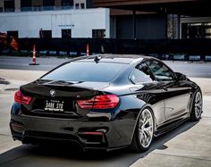 a black car parked on the side of a road next to an orange traffic cone