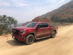 a red truck parked on the side of a dirt road
